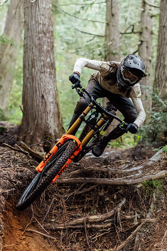 Mountainbiker im Wald fährt über Wurzeln