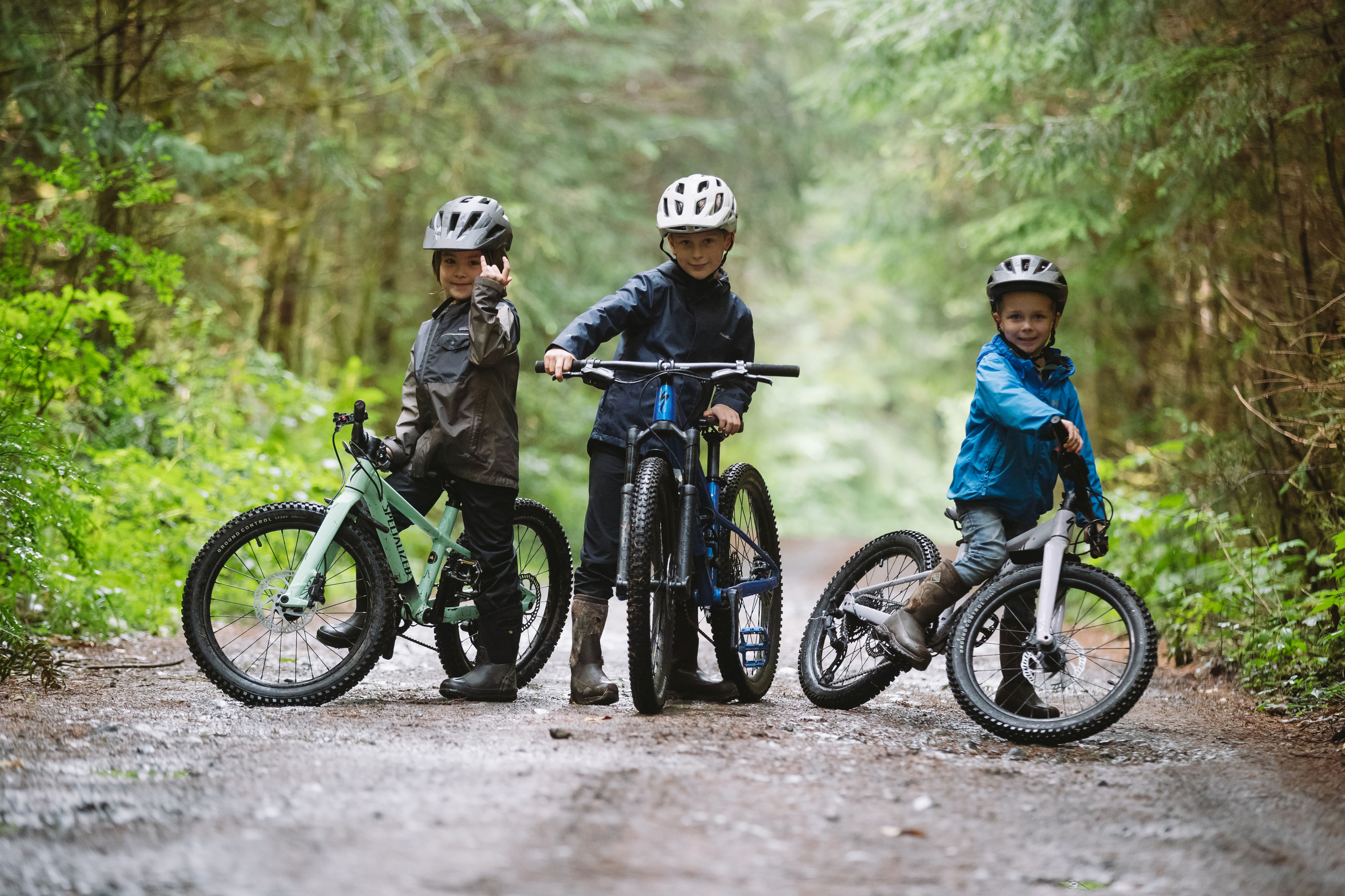 Drei Kinder stehend im Wald auf Mountainbikes